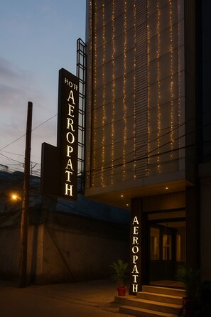 Ein modernes Gebäude mit einem Schild, auf dem „AEROPATH HOTEL“ steht, und dekorativer Lichterkette.