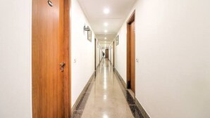 A long, well-lit hallway with wooden doors on both sides, leading to multiple rooms. - Pathway KDSON at Airport (New Delhi)