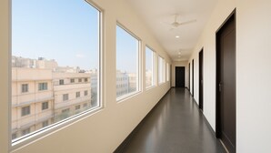 A long, narrow hallway with large windows on one side and a dark floor. - Pathway KDSON at Airport (New Delhi)