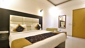 A modern hotel room with a large bed, a bedside table, a mirror, and a wooden door. - Pathway KDSON at Airport (New Delhi)