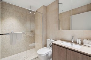 A modern bathroom with a glass-enclosed shower, a toilet, a sink, and a vanity with a mirror.
