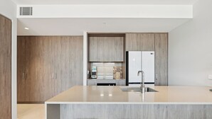 Una cocina moderna con armarios de madera, una isla integrada con fregadero y dos taburetes de bar.