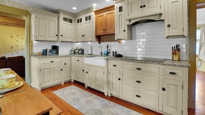 A kitchen with white cabinetry, a wooden countertop, and a white tiled backsplash. - Cottage at High Cross Farms | Front Porch (Mount Joy)