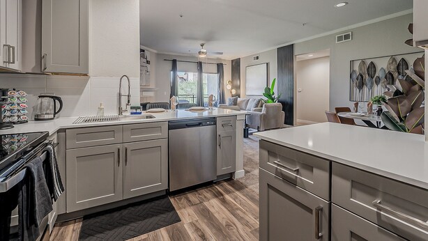 A modern kitchen with stainless steel appliances, a dishwasher, and a dining area with a table and chairs. - Cozy Scottsdale 2BR - 2BA/ Pool/Gym/Free Parking (Scottsdale)