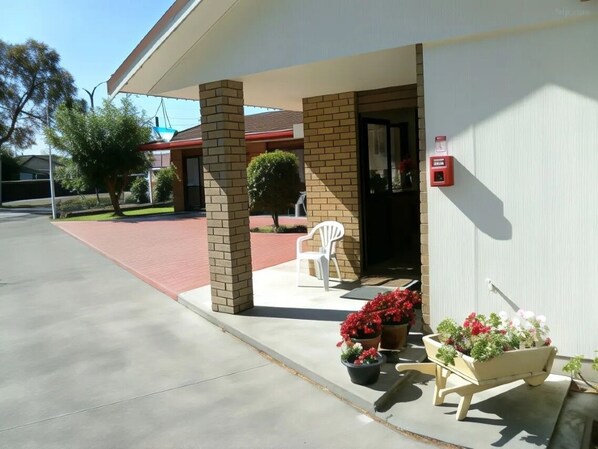 A building with a covered entrance, a brick facade, and a white chair outside.