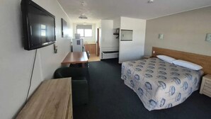 Une chambre d’hôtel équipée d’un lit, d’un bureau, d’une chaise, d’une télévision et d’une kitchenette.