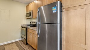 Une cuisine dotée de meubles en bois et d’appareils électroménagers en acier inoxydable, notamment un réfrigérateur, un four à micro-ondes et un four traditionnel.