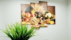 A dining area with a wall-mounted fruit and vegetable painting, a potted plant, and grey upholstered chairs. - Beauty Home 3Br/2Bath Nearby Downtown in San Jose (San Jose)