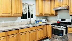 A kitchen with wooden cabinets, a stainless steel stove, and a window with curtains. - Beauty Home 3Br/2Bath Nearby Downtown in San Jose (San Jose)