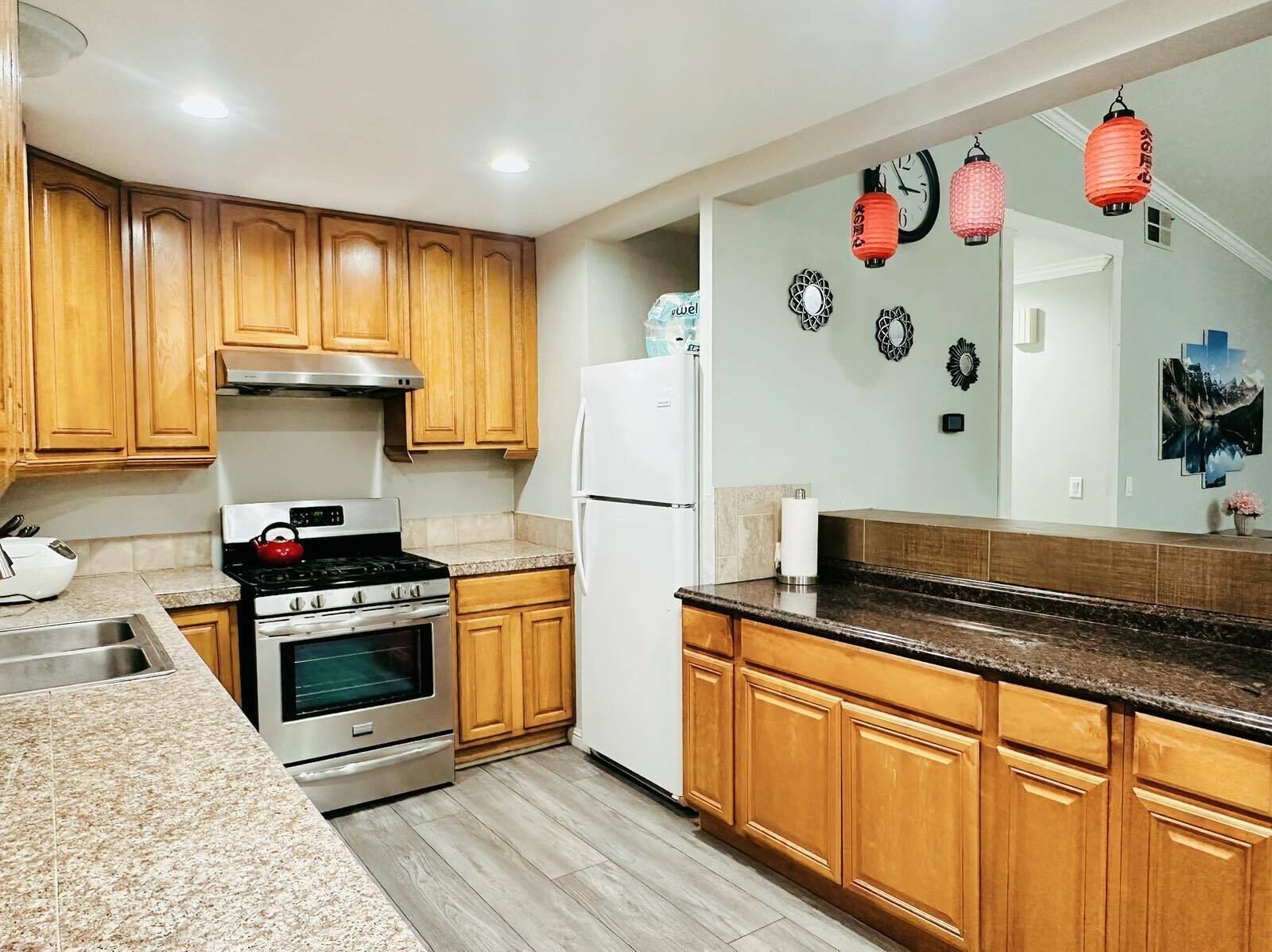A modern kitchen with wooden cabinets, stainless steel appliances, and decorative wall art.