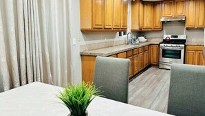A modern kitchen with wooden cabinets, a built-in oven, and a dining area with a table and chairs. - Beauty Home 3Br/2Bath Nearby Downtown in San Jose (San Jose)