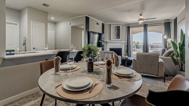 A modern dining area with a round table set for four, a fireplace, and a view of the city through large windows. - Scottsdale 2BR • Pool • Gym •Free Parking •Central (Scottsdale)
