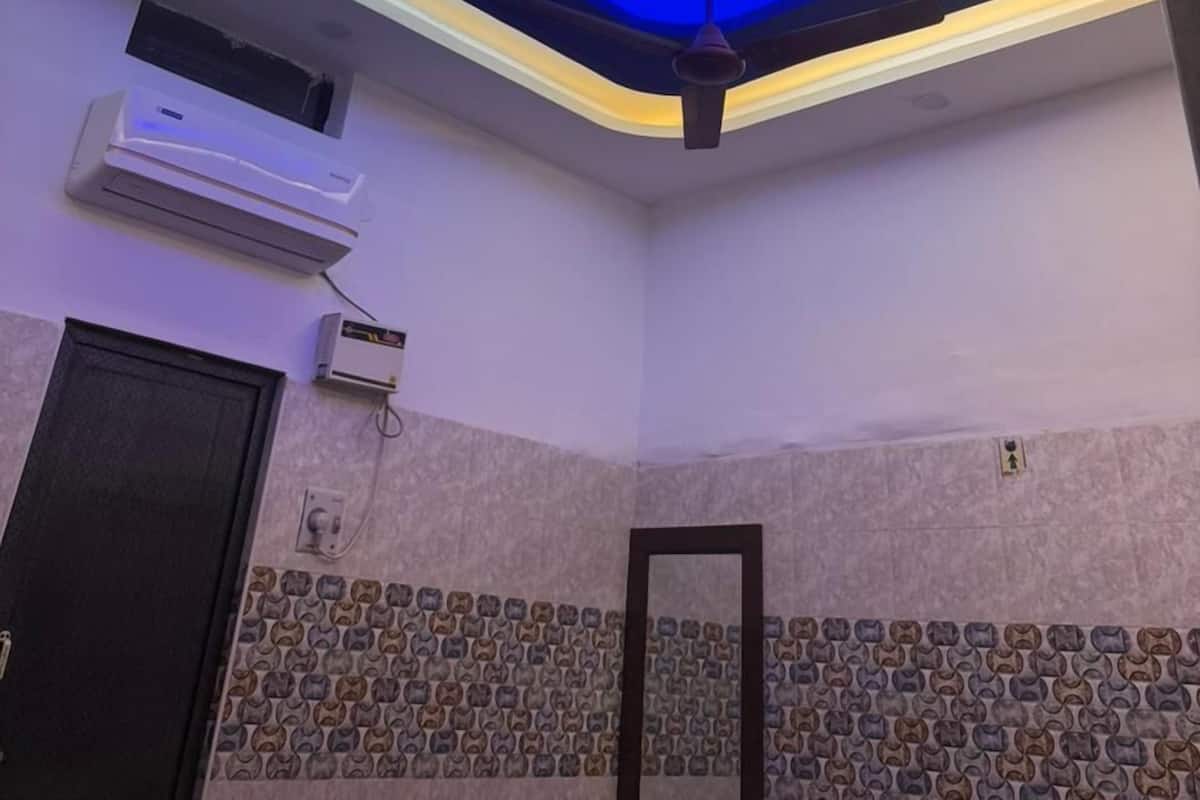 A room with a modern ceiling design featuring blue lighting, a ceiling fan, and an air conditioning unit.