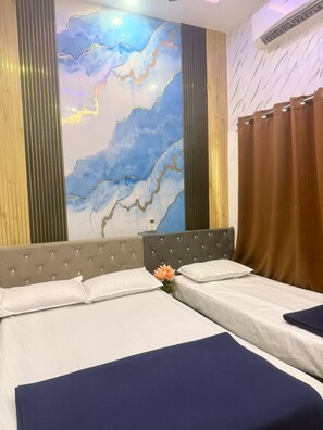 A hotel room with two beds, a marble wall mural, and a large window with curtains.