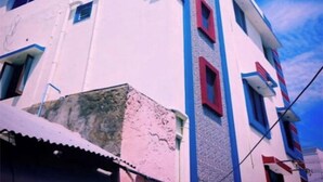 Ein mehrstöckiges Gebäude mit weißer Fassade und roten Akzenten, mit einer Reihe von Fenstern und einem sichtbaren Eingang.