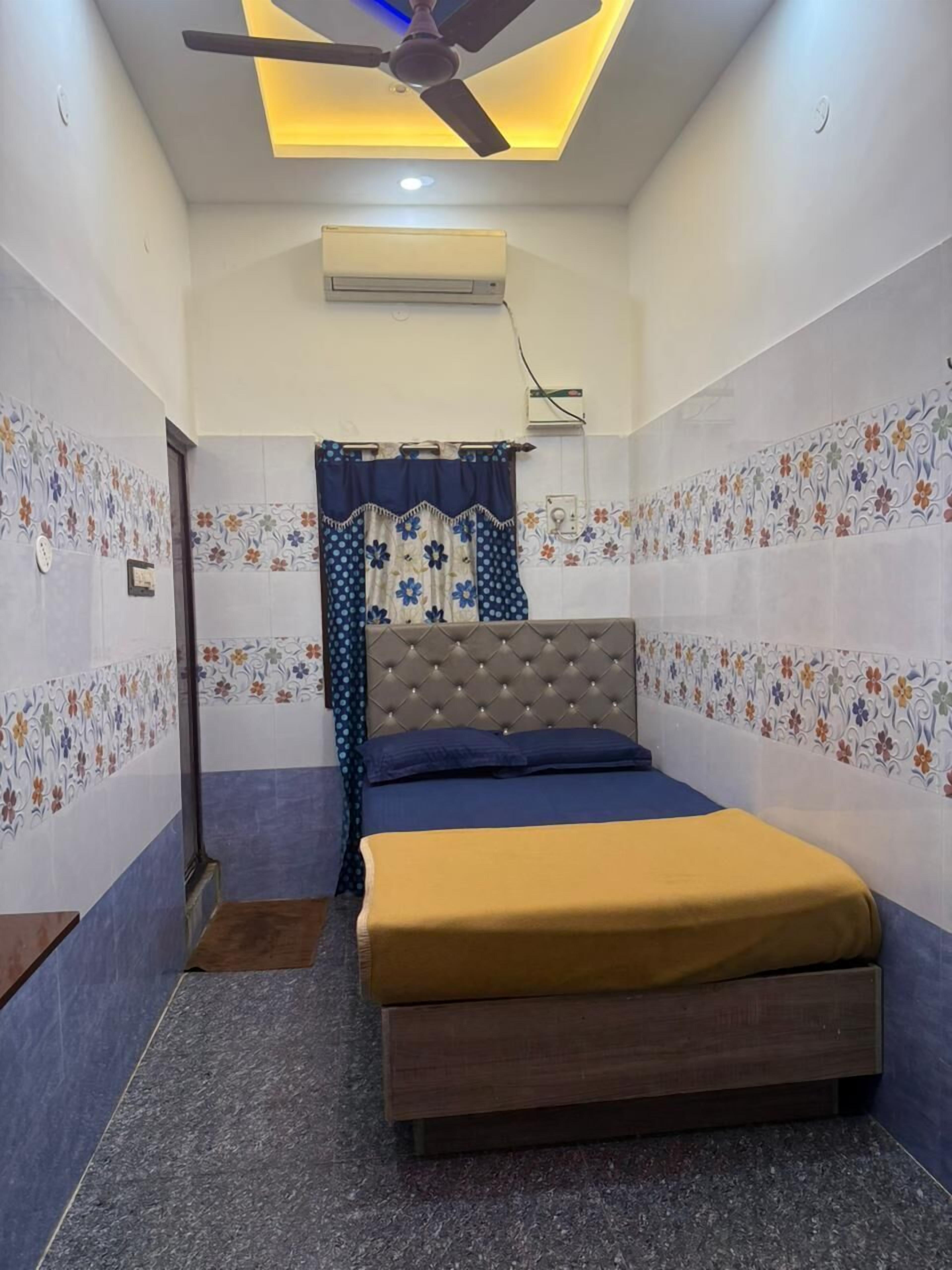 Un dormitorio con cama, ventilador de techo, equipo de aire acondicionado y paredes con diseño.