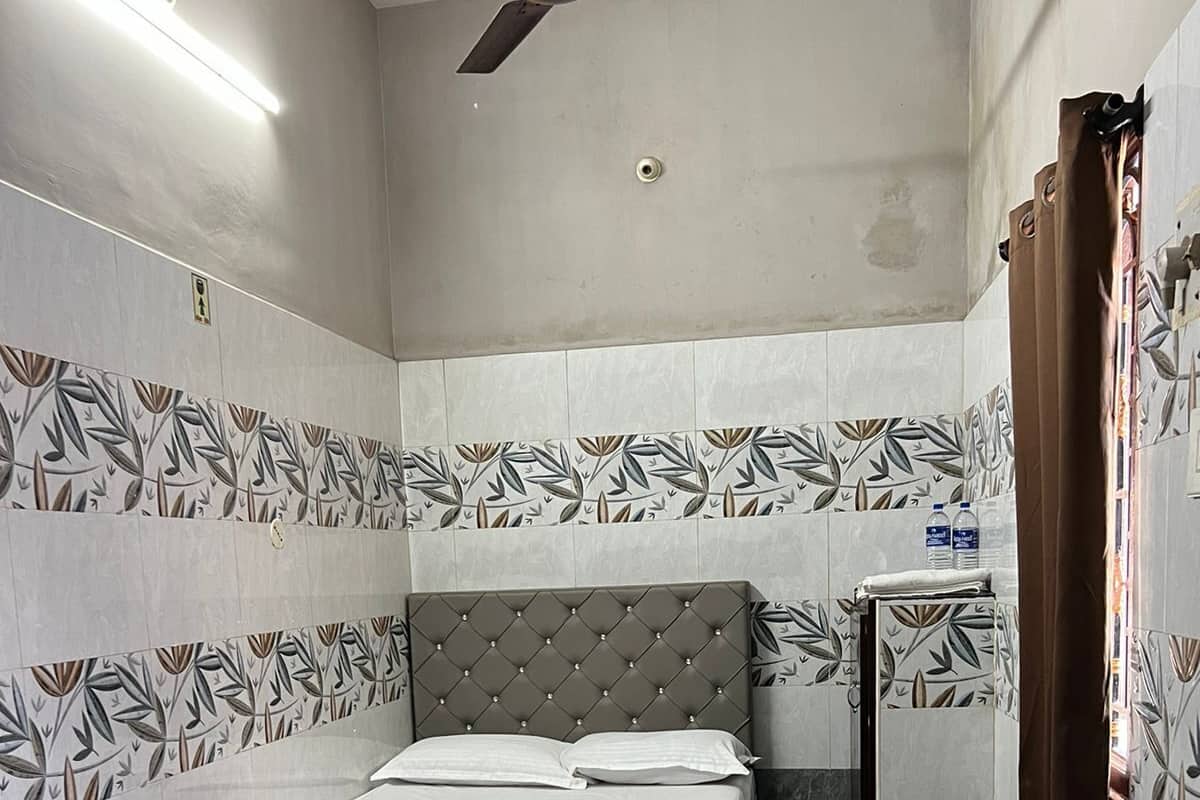 A hotel room with a bed, a ceiling fan, and patterned walls.