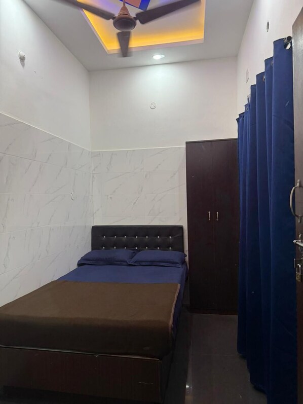 A bedroom with a bed, a ceiling fan, a door, and blue curtains.