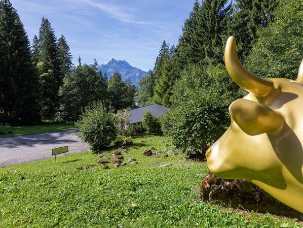 Eine Bullenstatue in einer grünen Landschaft mit Bäumen und einem Berg im Hintergrund.