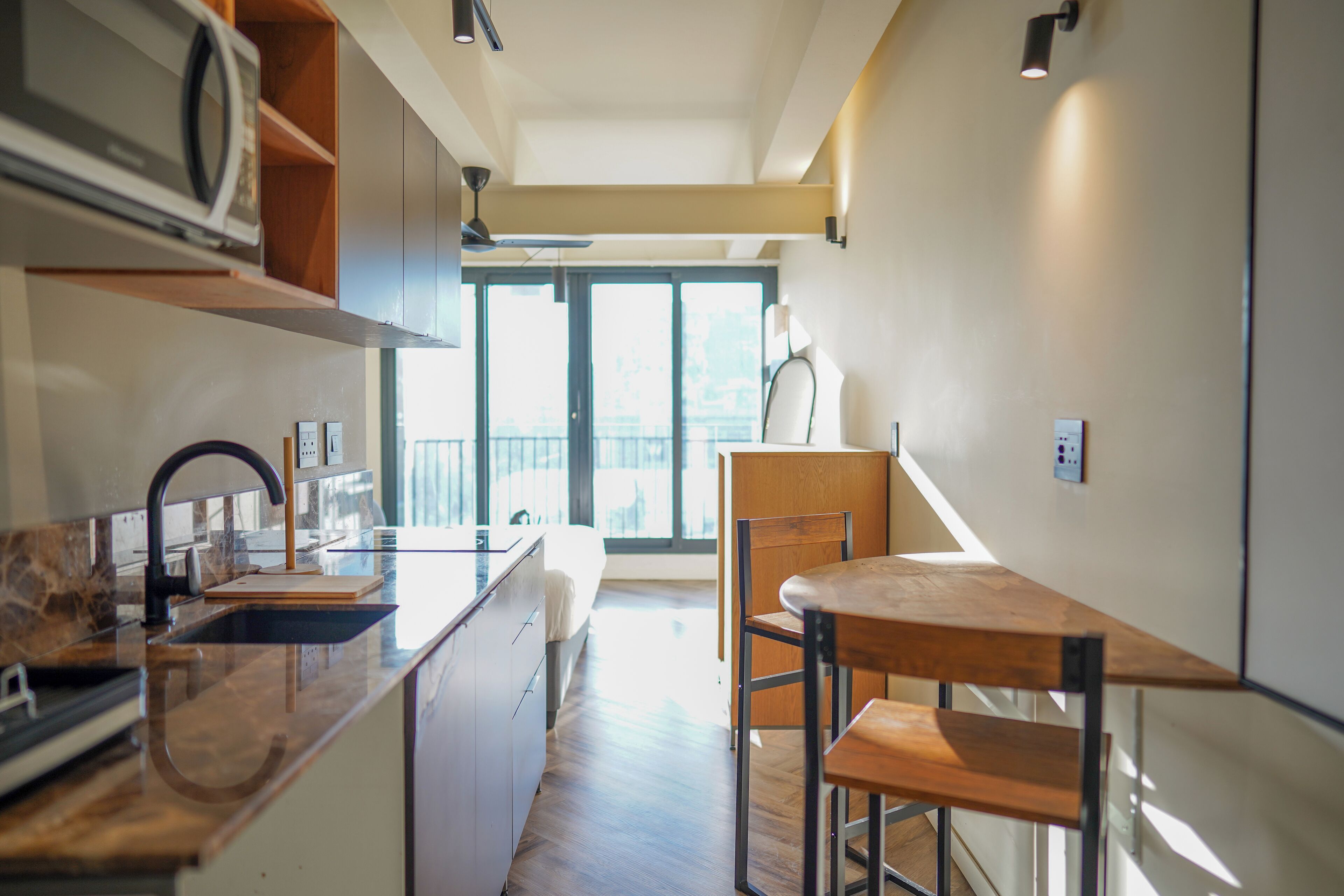 Una cocina moderna con una isla central, un comedor con mesa y sillas, y un amplio ventanal con vistas al exterior.