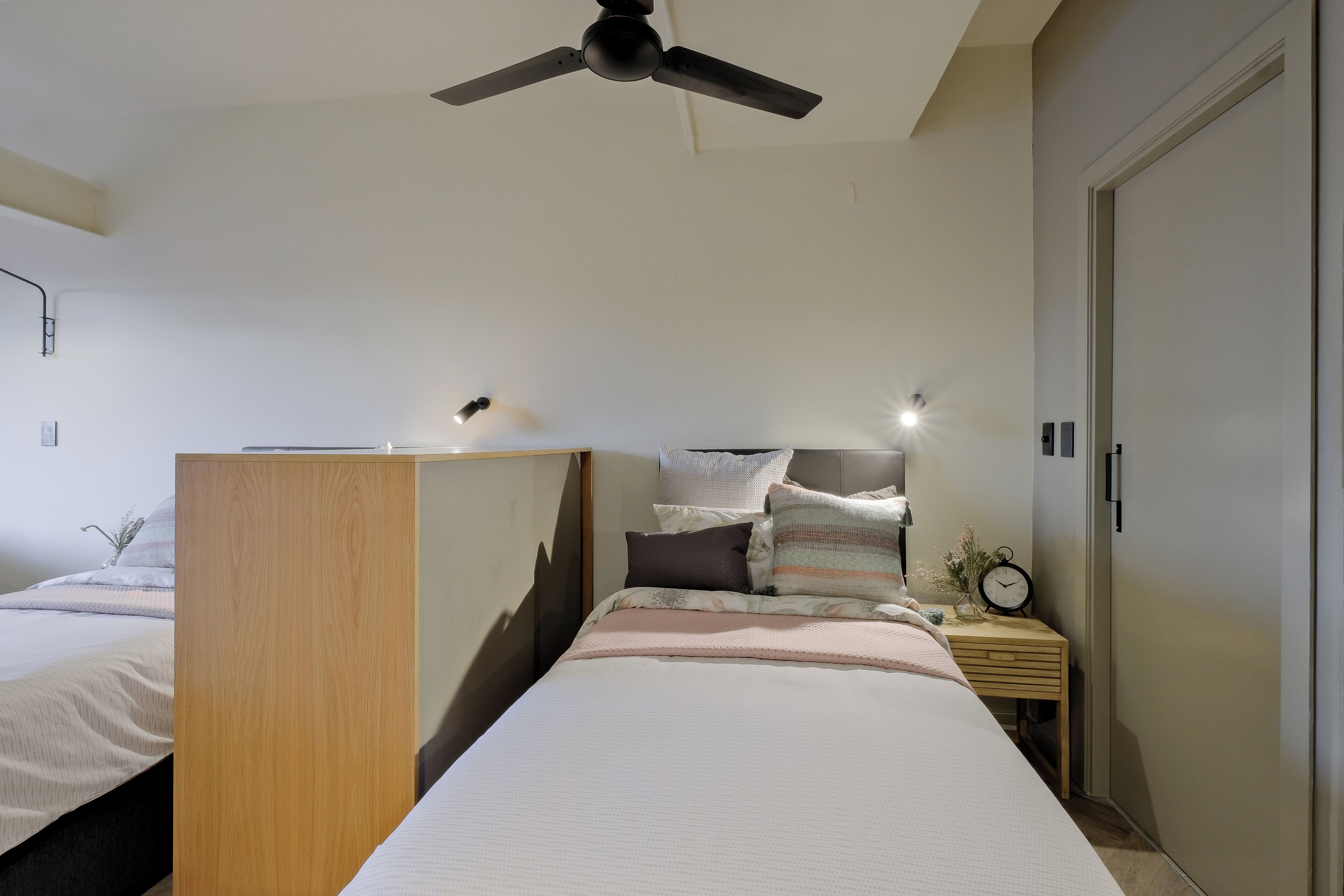 Un dormitorio con cama, mesita de noche y ventilador de techo.