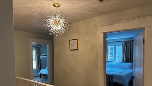 Een slaapkamer met een groot bed, een raam met gordijnen en een kroonluchter.