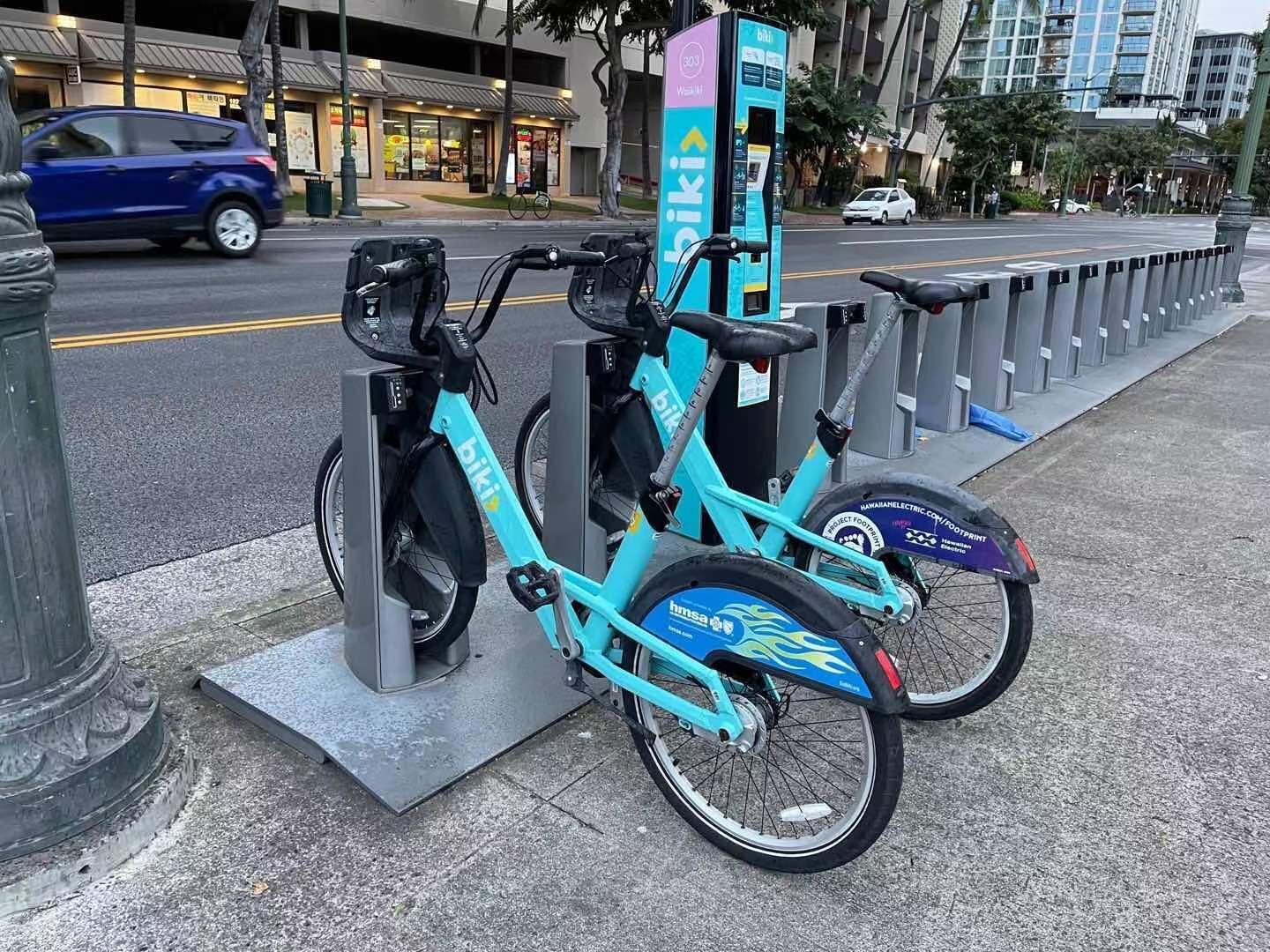 A turquoise bicycle parked at a public charging station.