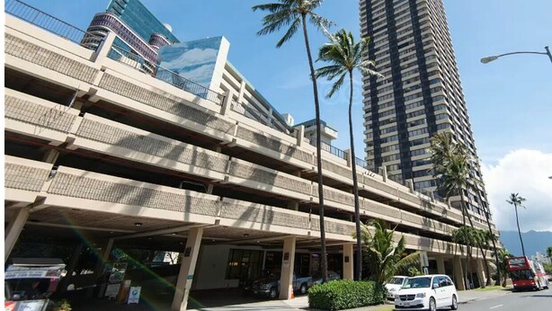 A multi-story parking structure with a modern building in the background.