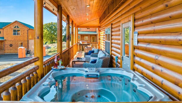 Een houten chalet met een hottub, buitenmeubels en uitzicht op een berg.