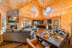 A spacious cabin interior with a dining area, kitchen, and living room. - Sleeps 12, Private Heated Indoor Pool, Hot Tub, Arcade, 3 Mi to Dollywood (Pigeon Forge)