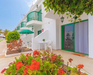 A modern hotel with a balcony, a small garden, and a dining area. - Sama Pool View y WiFi by iRent Fuerteventura (Corralejo)