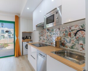 A modern kitchen with a microwave, sink, and wooden countertop. - Sama Pool View y WiFi by iRent Fuerteventura (Corralejo)