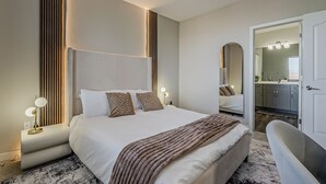 Ein modernes Hotelzimmer mit einem großen Bett, Nachttischlampen, einem Deckenventilator und einem durchgegangene Tür erkennbaren Badezimmer.
