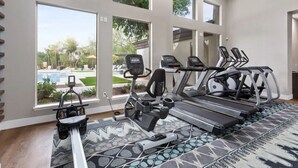 Ein Fitnessraum mit Laufbändern, Rudergerät und Hometrainer. Große Fenster bieten Blick ins Freie.