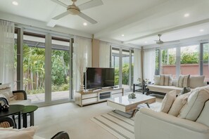 A spacious living room with a flat-screen TV, a sofa, a coffee table, and a ceiling fan. - Koson, Elegant 3 Bedroom Villa (Tambon Rawai)