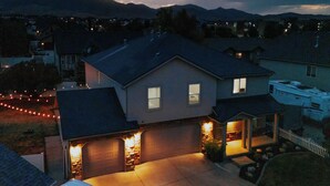 Ein zweigeschossiges Haus mit Garage, überdachter Veranda und gut beleuchteter Auffahrt.