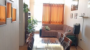 Una sala de estar con una mesa de comedor de vidrio, un sofá y un ventilador de techo.