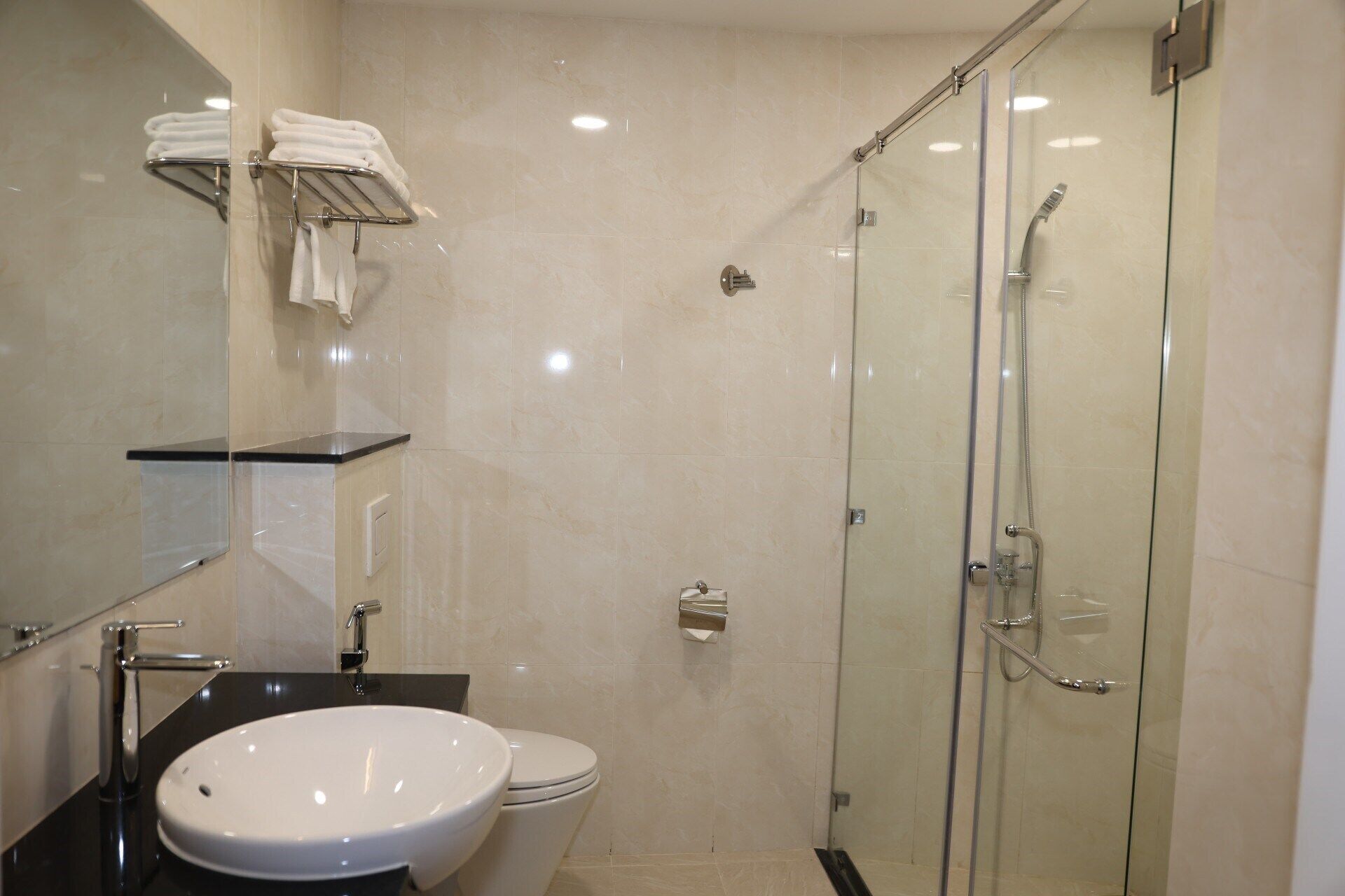Un baño moderno con ducha de vidrio, lavamanos blanco y retrete.