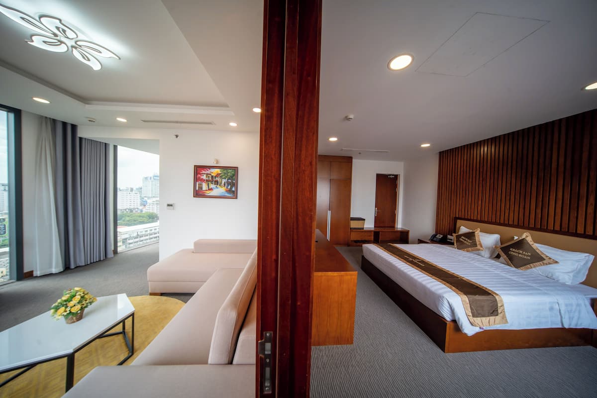 Une chambre d’hôtel moderne avec un grand lit, un canapé, une petite table et une vue sur la ville.