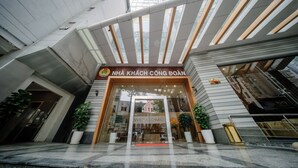 Der Eingang des Hotels Nha Kach Cong Doan mit modernem Design, mit einer Glasfassade und einem roten Teppich, der zum Eingang führt.