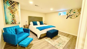 A modern bedroom with a large bed, a blue sofa, and a matching ottoman.