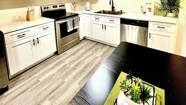 A modern kitchen with white cabinets, stainless steel appliances, and a black countertop.