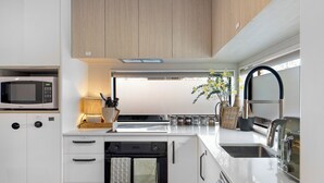 A modern kitchen with white cabinetry, a built-in microwave, a stove, and a sink. - Apartment on Short (Christchurch)