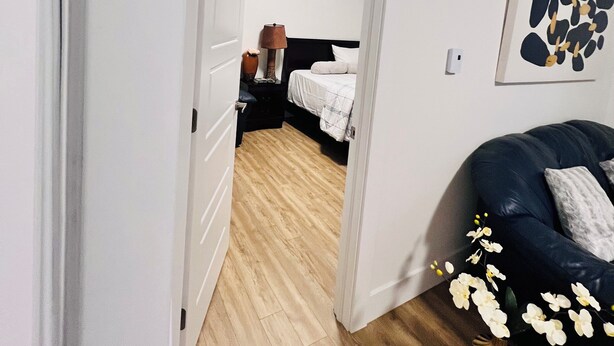 Un dormitorio con cama, mesita de noche, lámpara y una obra de arte colgada en la pared.