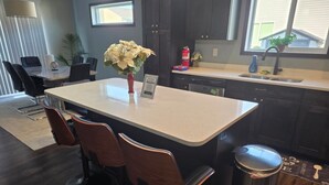 Een moderne keuken met donkerhouten kastjes, een wit aanrecht en een centraal eiland met barkrukken.