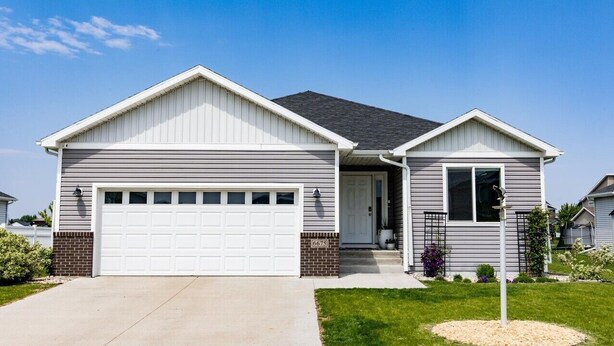 Een woonhuis met twee verdiepingen, een garage, een voortuin en een kleine aangebouwde garage.