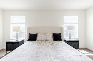 Une chambre à coucher avec un grand lit, deux tables de chevet et une fenêtre.