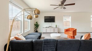 A modern living room with a sofa, armchair, and a ceiling fan. - Large new construction 3-bedroom near Hospital Hub (Bakersfield)
