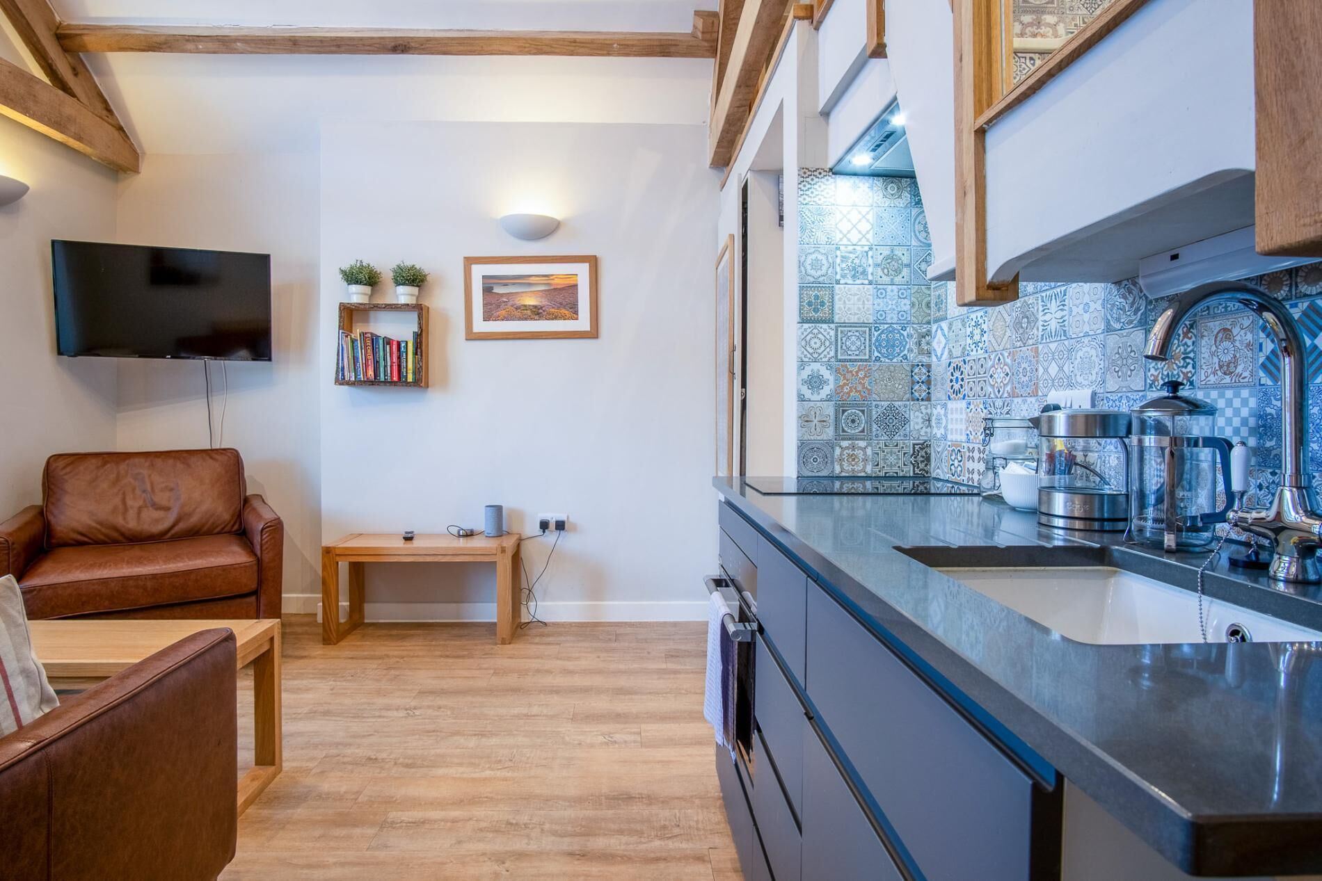 A modern kitchen with a tiled backsplash, a built-in oven, and a stainless steel sink.