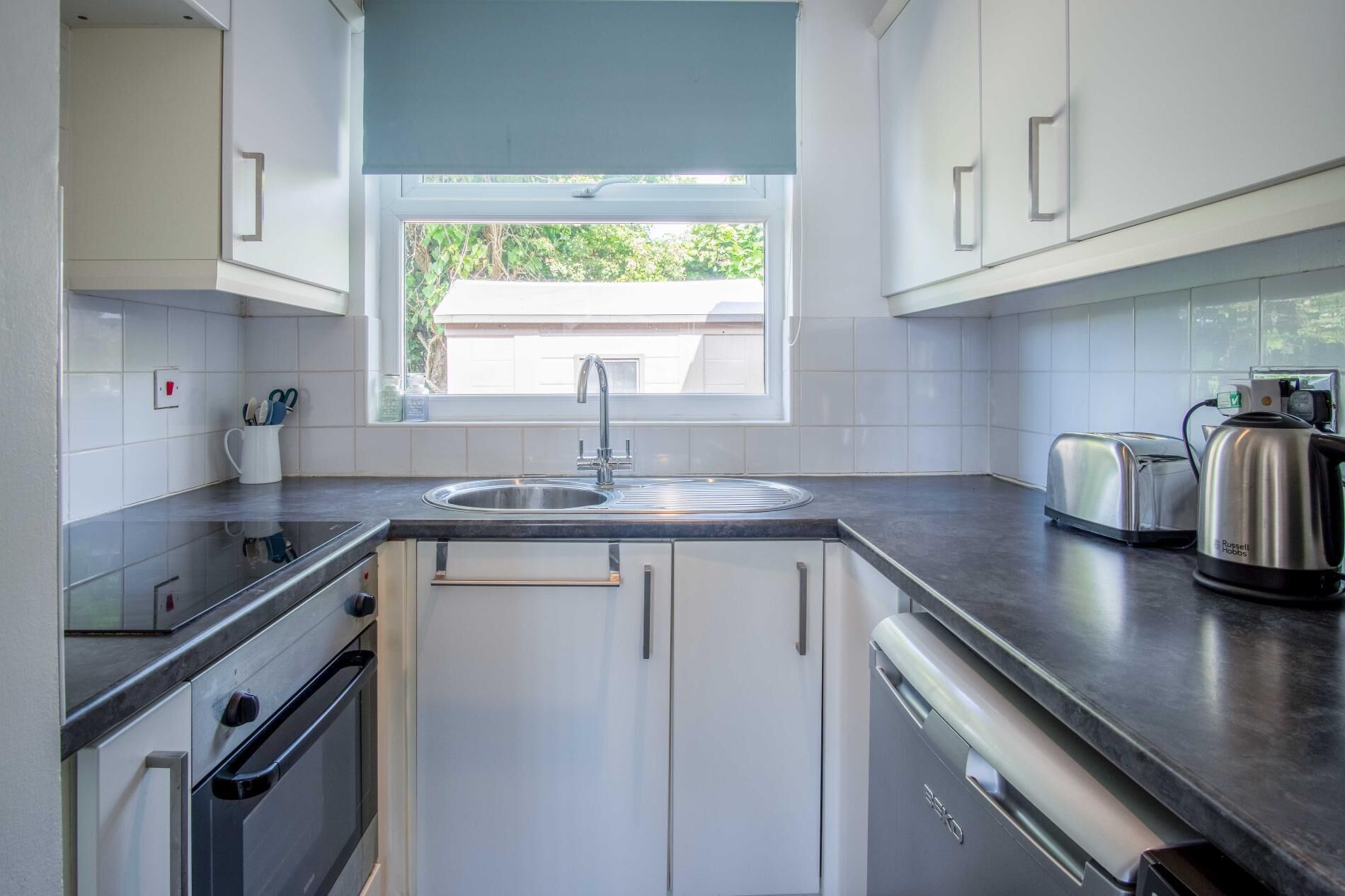 A modern kitchen with a built-in dishwasher, a sink, and a toaster.